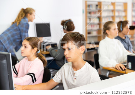 Young boys and girls using computers in library Young boys and girls using computers in library 112552878