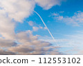 White clouds and condensation trail in the blue sky - cloudscape 112553102