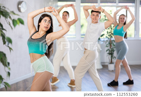 Girl teen perform choreographic exercise and teach energetic house dance with friends Girl teen perform choreographic exercise and teach energetic house dance with friends 112553260