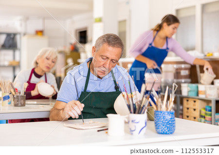 man potter carefully paints vase 112553317