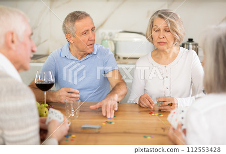 Group of friends playing poker cards and drinking wine at home Group of friends playing poker cards and drinking wine at home 112553428