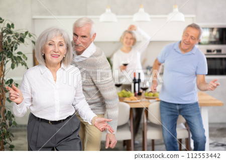Senior men and women have fun dancing during house party. 112553442