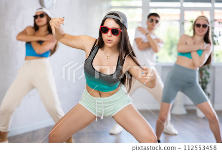 Group of young women and young guy in sunglasses dancing hip hop Group of young women and young guy in sunglasses dancing hip hop 112553458