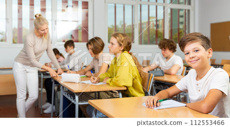 Young boy sitting at desk in classroom Young boy sitting at desk in classroom 112553466