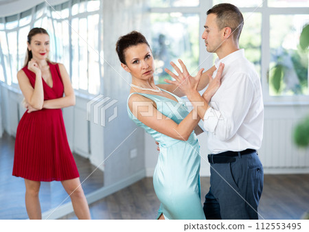 Coach, paired with man student, shows master class and explains technique of tango dance Coach, paired with man student, shows master class and explains technique of tango dance 112553495