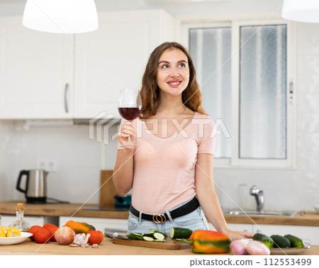 Portrait young woman with a glass of wine in the kitchen 112553499