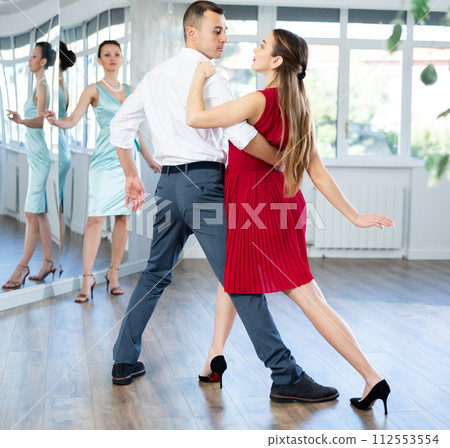 Couple in stage costumes learns tango dancing during individual lesson Couple in stage costumes learns tango dancing during individual lesson 112553554
