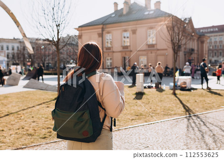 Young alone woman with backpack walking in sunny European city street 112553625