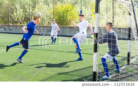 Heading ball towards the goal. Football match between two youth teams 112553636