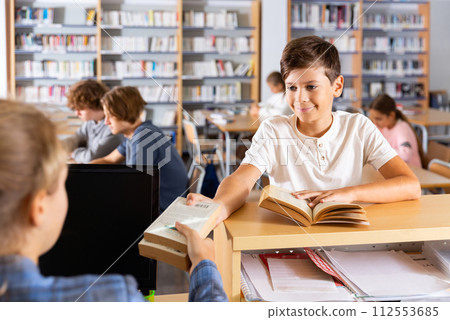 Boy giving books to librarian Boy giving books to librarian 112553685