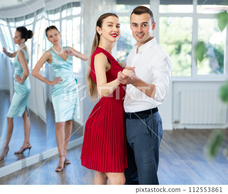Woman in red learning to dance waltz with man in studio Woman in red learning to dance waltz with man in studio 112553861