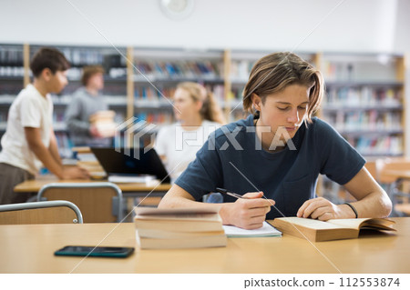 Teenager boy spending time in library Teenager boy spending time in library 112553874