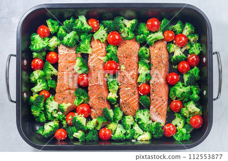 Raw salmon fillet with broccoli and tomato on frying tray, ready to bake, horizontal, top view 112553877
