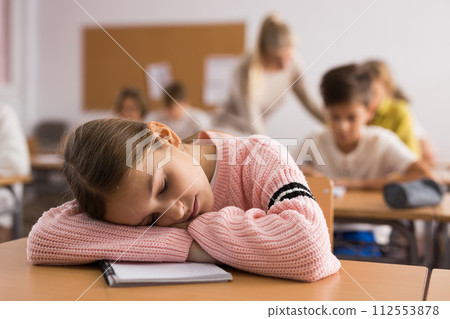 School girl lying and sleeping at desk 112553878