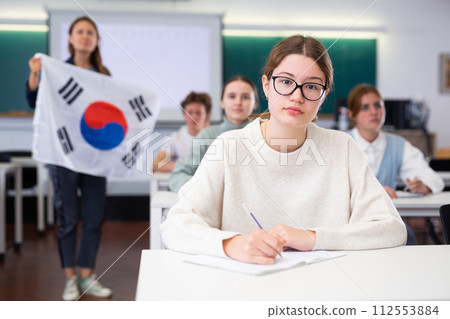 Teacher stands behind students with South Korean flag 112553884