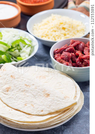 Many whole wheat flour tortillas and ingredients for tacos, fajitas or quesadilla, vertical Many whole wheat flour tortillas and ingredients for tacos, fajitas or quesadilla, vertical 112553891