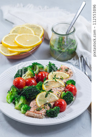 Baked salmon fillet with broccoli and tomato on plate, salmon steak with vegetables, vertical Baked salmon fillet with broccoli and tomato on plate, salmon steak with vegetables, vertical 112553896