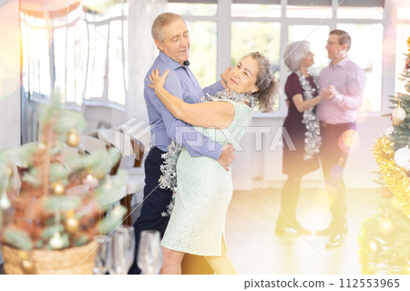 In studio decorated for New Year, elderly man and woman perky dance pair discofox. 112553965