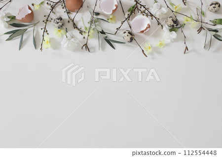 Spring frame, banner. Easter floral composition. Yellow primrose, white carnation flowers. Birch, olive tree branches, twigs. Quail, hen eggs shells isolated on white table background. Flat lay, top Spring frame, banner. Easter floral composition. Yellow primrose, white carnation flowers. Birch, olive tree branches, twigs. Quail, hen eggs shells isolated on white table background. Flat lay, top 112554448