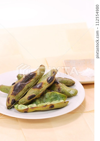 Grilled broad beans, burnt pods, beans inside, white plate Grilled broad beans, burnt pods, beans inside, white plate 112554980