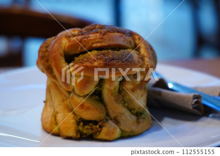 A close-up of a flaky croissant on a white plate with a knife and napkin. A close-up of a flaky croissant on a white plate with a knife and napkin. 112555155