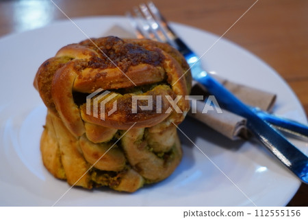 A close-up of a flaky croissant on a white plate with a knife and napkin. 112555156