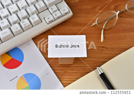 Desk with a card that says Bullshit Jobs Desk with a card that says Bullshit Jobs 112555851