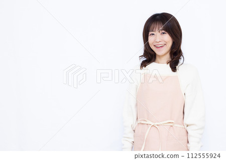 Housewife in an apron smiling at the camera Housewife in an apron smiling at the camera 112555924