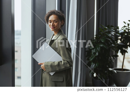 Woman with paper by window in formal wear, interior design event 112556127