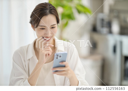A woman looking at her smartphone in the living room 112556163