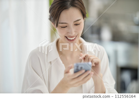 A woman looking at her smartphone in the living room A woman looking at her smartphone in the living room 112556164