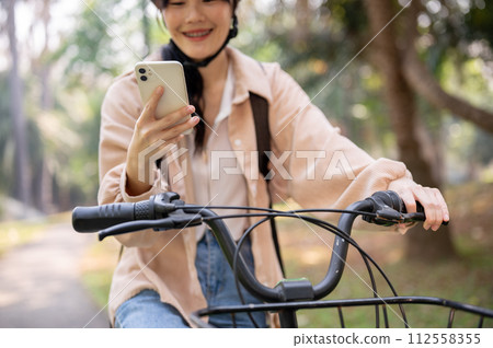 A happy young Asian female college student is using her smartphone while on her way to campus. A happy young Asian female college student is using her smartphone while on her way to campus. 112558355