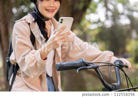 A happy young Asian female college student is using her smartphone while on her way to campus. A happy young Asian female college student is using her smartphone while on her way to campus. 112558356