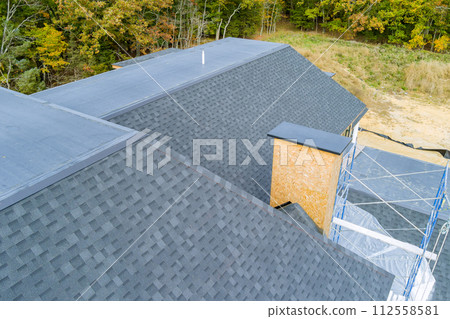 An asphalt shingle roof covers roof of newly built house 112558581