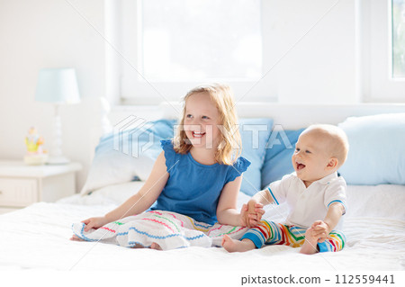Kids playing on parents bed 112559441