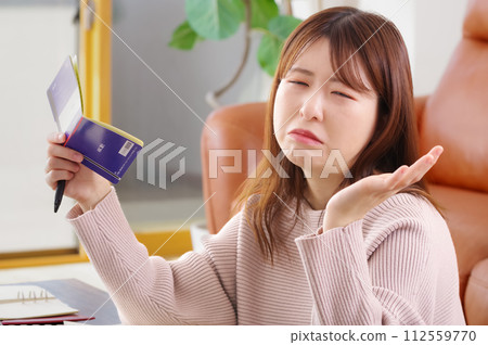 A woman holding a bankbook and looking troubled 112559770