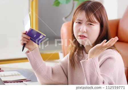A woman holding a bankbook and looking troubled A woman holding a bankbook and looking troubled 112559771