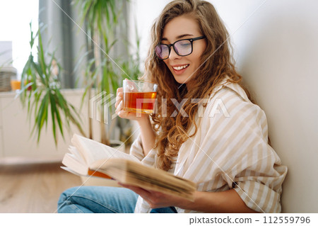 Happy woman drinks hot drink and sits on phone, reads book, flips through magazine. Vacation concept Happy woman drinks hot drink and sits on phone, reads book, flips through magazine. Vacation concept 112559796
