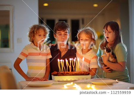 Teenager boy birthday. Siblings blow cake candles 112559939