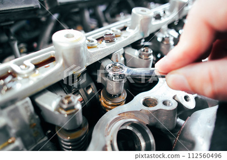 Car mechanic checking and adjusting valves of car engine Car mechanic checking and adjusting valves of car engine 112560496