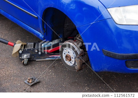 A wheel is removed from a blue car A wheel is removed from a blue car 112561572