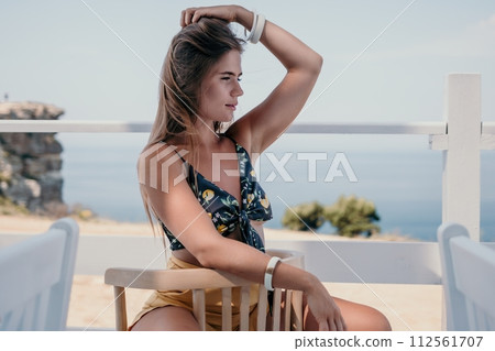 Happy woman portrait in cafe. Boho chic fashion style. Outdoor photo of young happy woman with long hair, sunny weather outdoors sitting in modern cafe. 112561707