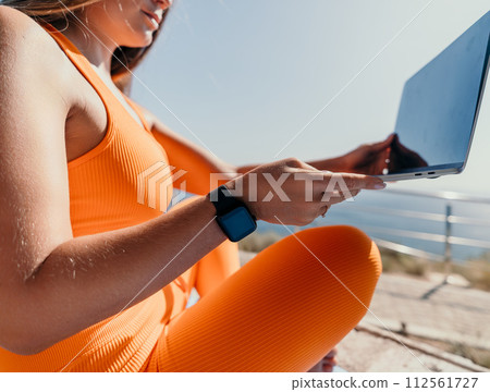 Woman laptop sea. Working remotely on seashore. Happy successful woman female freelancer working on laptop by the sea at sunset, makes a business transaction online. Freelance, remote work on vacation Woman laptop sea. Working remotely on seashore. Happy successful woman female freelancer working on laptop by the sea at sunset, makes a business transaction online. Freelance, remote work on vacation 112561727