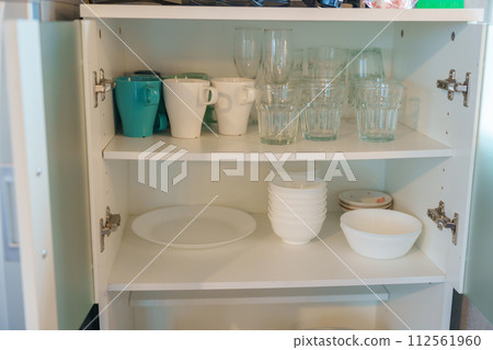 Set of dishes and glass in cabinet at apartment or Home. Kitchenware, dinnerware, lifestyle domestic concept 112561960
