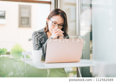 A woman in a suit thinking while using a laptop in the office 112562089