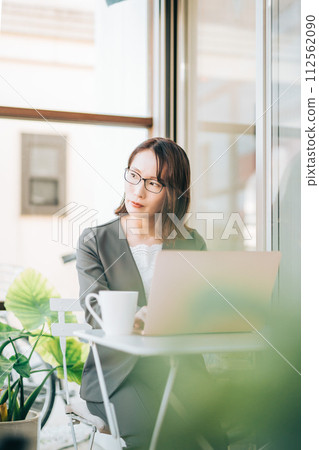 A woman in a suit thinking while using a laptop in the office 112562090