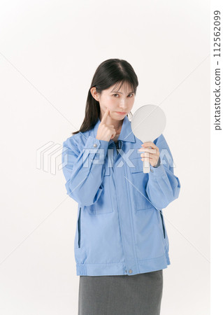 A woman in work clothes looking in the mirror 112562099