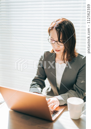一位穿著西裝的女士在辦公室使用筆記型電腦思考 一位穿著西裝的女士在辦公室使用筆記型電腦思考 112562389