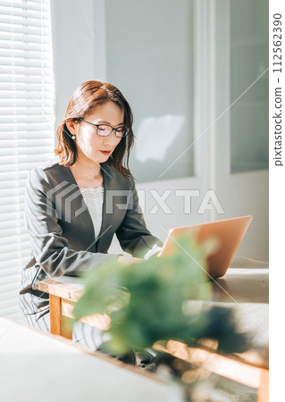 A woman in a suit works while using a laptop in the office 112562390