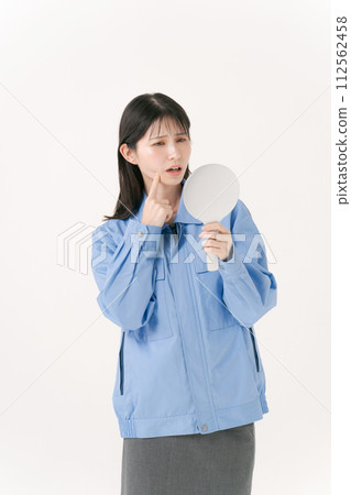 A woman wearing work clothes looking in the mirror 112562458